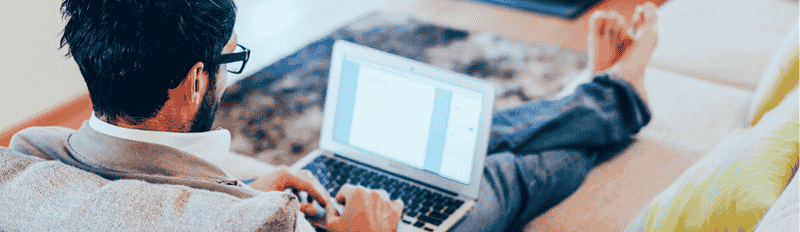 man lounging on couch with laptop